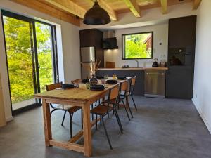 a kitchen with a wooden table and some chairs at La Fruitière de Vérel, logements modulables neufs, calmes, entre lac et montagne, max 11 personnes in Rovagny