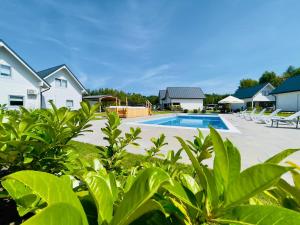 a swimming pool in a yard next to a house at Białe Domki Paula SPA Niechorze in Niechorze