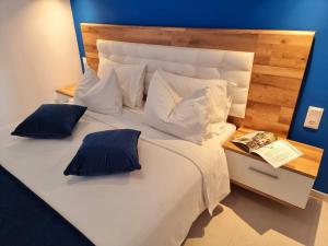 a large white bed with pillows and a book on it at Hotel Nefeli in Volos