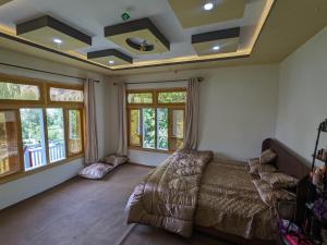 a bedroom with a bed and a couch and windows at Alpine Resort Khaplu in Khaplu