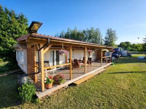 a tiny house with a deck in a yard at Mazury Kemp Jedwabno in Jedwabno