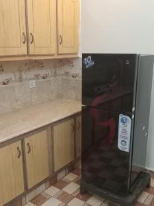 a black refrigerator in a kitchen with wooden cabinets at Abbasi guest house in Murree