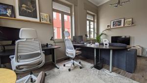 an office with two desks and two chairs and a tv at dvnest - Premium 1BR Apartment with River View! in Porto