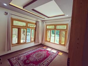 a room with windows and a rug on the floor at Alpine Resort Khaplu in Khaplu