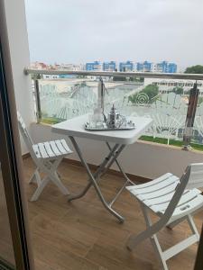 d'une table blanche et de deux chaises sur un balcon. dans l'établissement Apartamento perla del mar, à Martil
