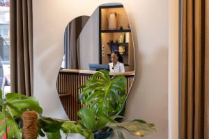 a woman sitting at a desk in front of a mirror at Hotel le 46 R&eacute;novation 2024 in Paris