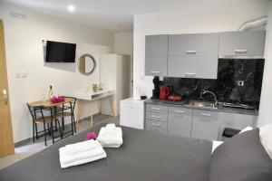 a kitchen with white cabinets and a table with towels at Aloha Inn in Artemida