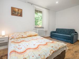 a bedroom with a large bed and a blue couch at Holiday Home Perła by Interhome in Trygort