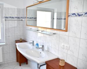 ein weißes Badezimmer mit Waschbecken und Spiegel in der Unterkunft Ferienhaus Fiete 2 in Sagard + 29 Fotos