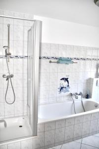 ein weißes Badezimmer mit Badewanne und Dusche in der Unterkunft Ferienhaus Fiete 2 in Sagard