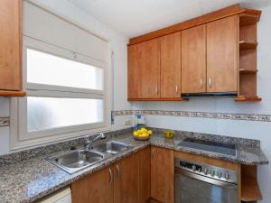 a kitchen with wooden cabinets and a sink and a window at Apartment Fénix Marina by Interhome in L'Escala