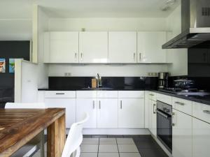 eine Küche mit weißen Schränken und einem Holztisch in der Unterkunft Holiday Home Bungalowpark It Wiid by Interhome in Eernewoude + 13 Fotos