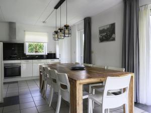 ein Esszimmer mit einem Holztisch und weißen Stühlen in der Unterkunft Holiday Home Bungalowpark It Wiid by Interhome in Eernewoude