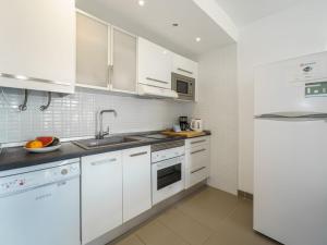 Una cocina blanca con gabinetes blancos y un fregadero. en Apartment Oratge Beach Views by Interhome, en Puerto Pollensa