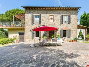 a patio with a red umbrella in front of a house at Holiday Home Tenuta La Colonna by Interhome in Ponte di Masino