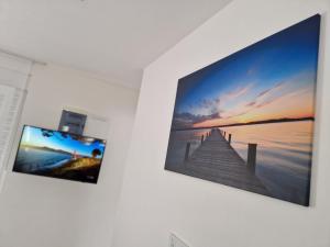 a tv hanging on a wall with two pictures of a pier at B&L Apartments in Vir