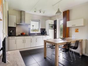 a kitchen with white cabinets and a wooden table at Holiday Home Bungalowpark It Wiid by Interhome in Eernewoude +17 photos