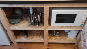a cabinet with a microwave and some utensils at La cabane en bois in Tourves