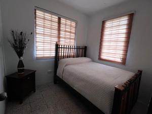 a bedroom with a bed and two windows at Trujillo House Vacation in Trujillo Alto