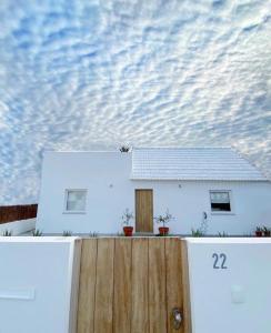a white house with a wooden fence in front of it at Comporta Cottage in Montevil