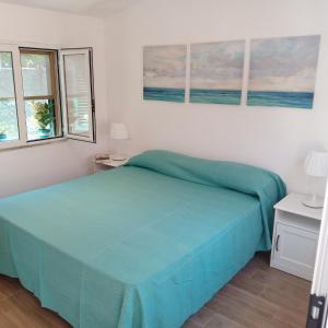 una camera con un letto blu e due finestre di Argentario Cottage a Giannella