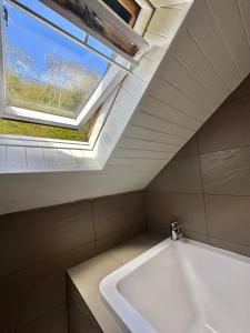 a bathroom with a white bath tub and a skylight at The Tobermory Hotel in Tobermory