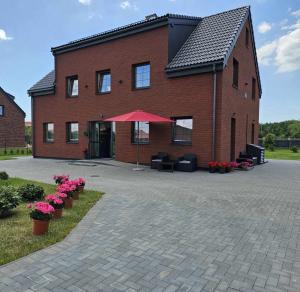a brick building with a red umbrella in front of it at Akvamarinas in Karklė