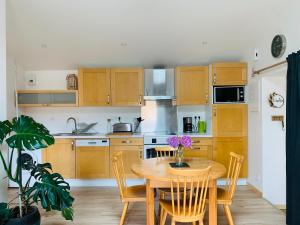 a kitchen with wooden cabinets and a wooden table with chairs at Le Solier, gîte à la campagne in Frossay