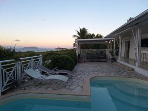 una piscina con sedie e una casa di Villa Muscade guadeloupe, piscine, vue mer et accès plage a Saint-François