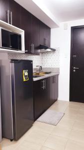 a kitchen with black cabinets and a black refrigerator at 1BR Cozy Condo at Kasara Urban Resort Pasig City in Manila