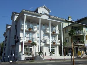 a large white building with potted plants on the balconies at Hotel Kralj in Vrnjačka Banja