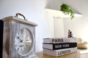 a clock sitting on top of a stack of books at Spacious 2 Bed Flat - 5 mins to St Helens Centre - Free Parking in Saint Helens +4 photos