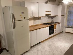 a kitchen with white cabinets and a refrigerator at Loft via Jesi a Correggio in Correggio