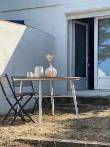 une table avec un vase dessus à côté d'un bâtiment dans l'établissement L'aventurine NO, à Barbâtre