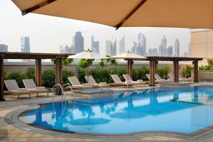 une piscine avec une vue sur les toits de la ville en arrière-plan dans l'établissement Crowne Plaza - Dubai Jumeirah, an IHG Hotel, à Dubaï