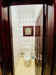 a bathroom with a toilet in a room with blue tiles at Chez soi loin de chez soi in Pointe-Noire