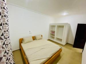 a small room with a bed and a cabinet at Chez soi loin de chez soi in Pointe-Noire +2 photos