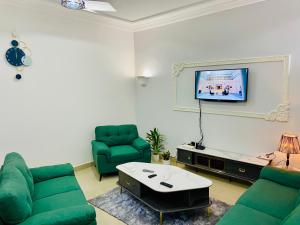 a living room with two green chairs and a tv at Chez soi loin de chez soi in Pointe-Noire