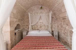 Un dormitorio con una cama en una pared de piedra. en Profumo di Pietra, en Martina Franca