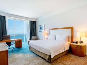 een hotelkamer met een groot bed en een bureau bij Hilton Doha in Doha