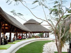 a resort with grass and straw umbrellas at Hilton Doha in Doha