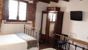 um quarto com uma cama e uma televisão na parede em Hotel Rural El secreto del Castillo em Maderuelo