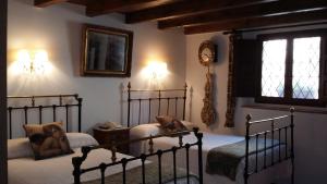 a bedroom with two beds and a clock on the wall at Hotel Rural El secreto del Castillo in Maderuelo