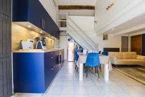 a kitchen with blue cabinets and a table with blue chairs at Gite Grand Luberon chez Manon en Luberon - Vacation rental in guest house in Lagnes