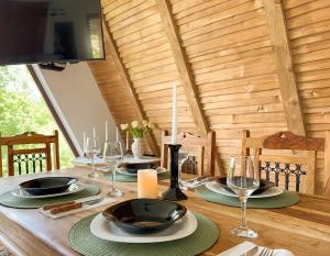 un tavolo di legno con sopra piatti e bicchieri da vino di Dream Cottage a Paltin