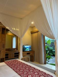 a bedroom with a canopy bed and a television at Dales Villa in Ubud