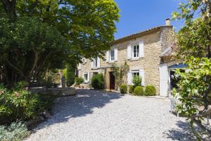 zewnętrzny widok na kamienny dom z podjazdem w obiekcie Chambre d'hôtes - B&B - Fleur de coton chez Manon en Luberon w mieście Lagnes