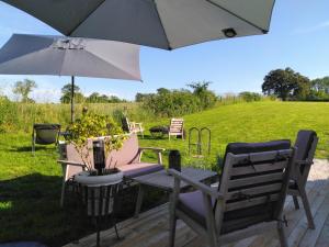 a table and chairs under an umbrella on a patio at Caravane romantique " La Seventies" avec jacuzzi privatif in Lapalisse
