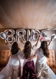 three girls sitting on a bed with a sign that says rave at Milan Suite Hotel in Milan