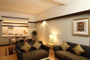 a living room with two couches and a dining room at L'Arabia Hotel Apartments in Abu Dhabi